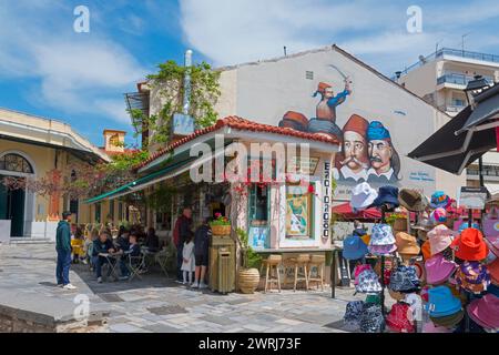 Un accogliente negozio di snack sotto un cielo blu in una giornata di sole, accanto ai graffiti con 5 eroi della rivoluzione greca del 1821 sulla piazza del 23 marzo Foto Stock