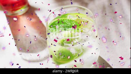 Immagine di coriandoli che cadono e cocktail su sfondo bianco Foto Stock