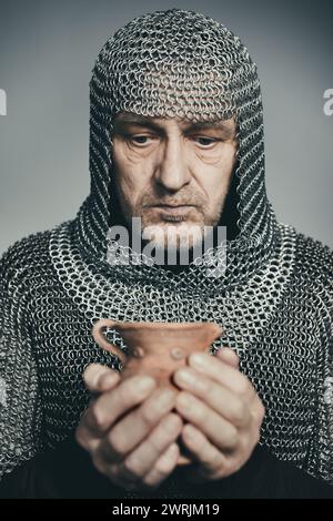 Fanteria medievale uomo armato vestito con armatura a catena che tiene in mano la caraffa d'argilla Foto Stock