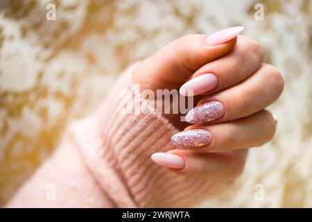 Un'immagine con la mano di una donna con splendide unghie in gel rosa, meticolosamente dipinte e adornate con eleganti glitter multicolore. La mano è ben m Foto Stock
