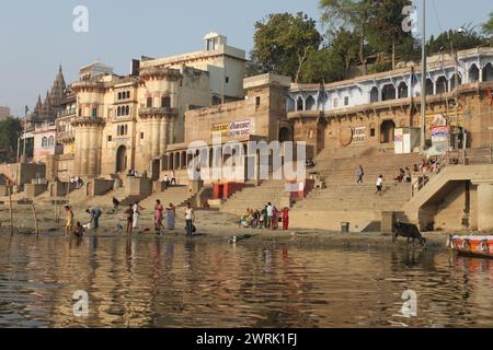 Varanasi, India - 13 marzo 2019: Vita quotidiana a Reewa Ghat sulle rive del fiume santo Gange a Varanasi all'alba. Vista frontale delle scale Foto Stock