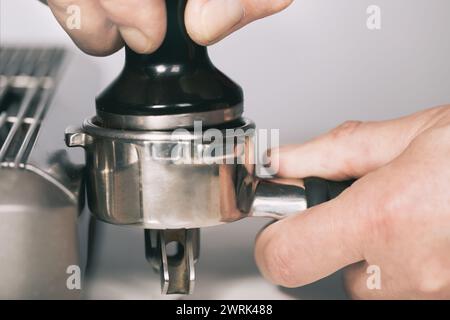 Premere il caffè macinato nell'impugnatura per estrarre il caffè nella macchina espresso Foto Stock