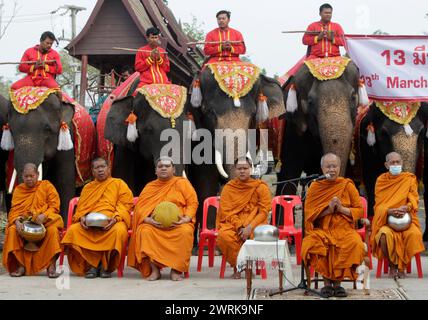 Ayutthaya, Thailandia. 13 marzo 2024. I monaci buddisti siedono di fronte agli elefanti durante la celebrazione nazionale del giorno degli elefanti della Thailandia nell'antica città di Ayutthaya. I thailandesi hanno onorato l'elefante lunedì con frutta speciale e cerimonie buddiste in tutto il paese per rendere omaggio ai loro animali nazionali. Credito: SOPA Images Limited/Alamy Live News Foto Stock