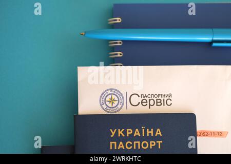 KIEV, UCRAINA - 27 NOVEMBRE 2023 logo del servizio passaporti con passaporto ucraino internazionale e penna sul tavolo Foto Stock