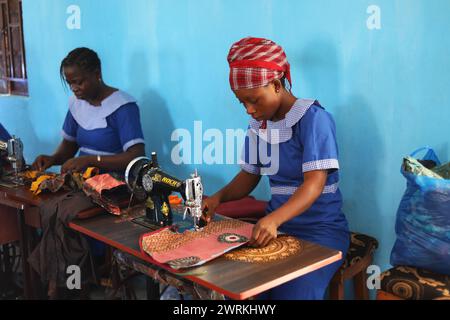 Donne e bambini immaginati di lavorare a mano per realizzare camicie all'Unione delle madri di Bo, Sierra Leone, Africa. Foto Stock