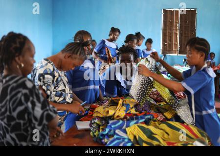 Donne e bambini immaginati di lavorare a mano per realizzare camicie all'Unione delle madri di Bo, Sierra Leone, Africa. Foto Stock