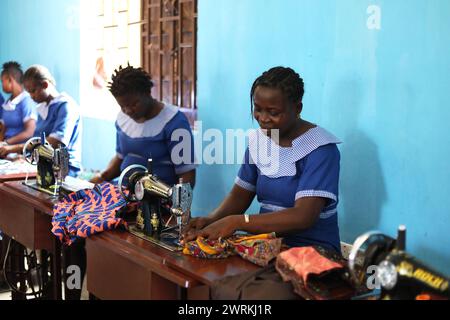 Donne e bambini immaginati di lavorare a mano per realizzare camicie all'Unione delle madri di Bo, Sierra Leone, Africa. Foto Stock