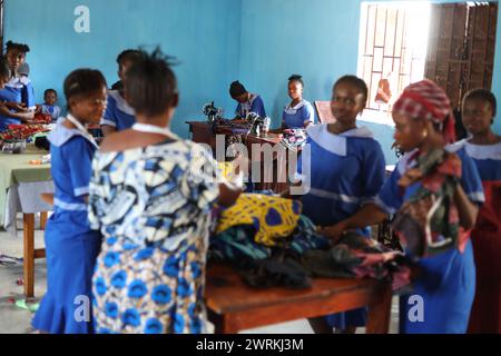 Donne e bambini immaginati di lavorare a mano per realizzare camicie all'Unione delle madri di Bo, Sierra Leone, Africa. Foto Stock