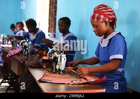 Donne e bambini immaginati di lavorare a mano per realizzare camicie all'Unione delle madri di Bo, Sierra Leone, Africa. Foto Stock