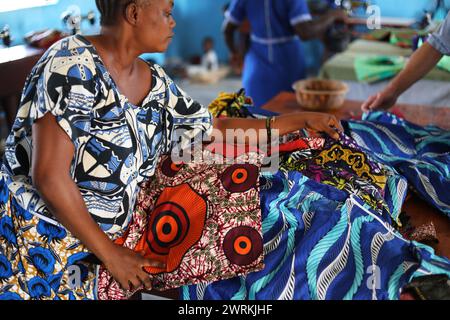 Donne e bambini immaginati di lavorare a mano per realizzare camicie all'Unione delle madri di Bo, Sierra Leone, Africa. Foto Stock