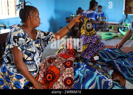 Donne e bambini immaginati di lavorare a mano per realizzare camicie all'Unione delle madri di Bo, Sierra Leone, Africa. Foto Stock