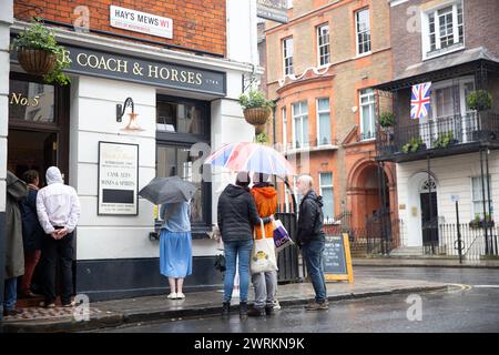 La gente guarda l'incoronazione di re Carlo III sullo schermo in un pub nel centro di Londra. Foto Stock