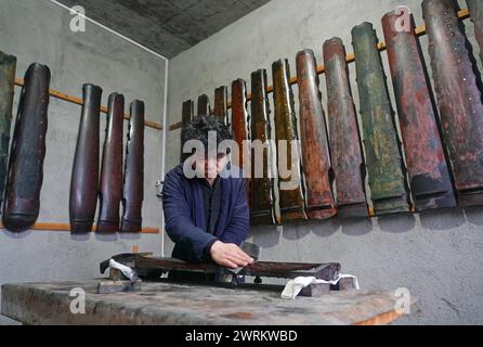 (240313) -- NANCHANG, 13 marzo 2024 (Xinhua) -- Feng Yihua lucida il corpo di un Guqin nel suo studio di Guqin nella contea di Yihuang, nella provincia di Jiangxi, nella Cina orientale, 7 marzo 2024. Il Guqin, uno strumento cinese tradizionale a sette corde a pizzico, vanta una storia di oltre 3.000 anni. Feng Yihua, un produttore di Guqin di 38 anni, proviene dalla contea di Yihuang, nella provincia di Jiangxi nella Cina orientale. Influenzato dalla sua famiglia, Feng iniziò a studiare il Guqin all'età di 18 anni. In seguito si trasferì a Shanghai per fare l'apprendista sotto un maestro nell'artigianato di Guqin. "Creare un Guqin a mano richiede una lacca grezza, che iniziale Foto Stock