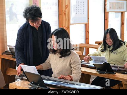 (240313) -- NANCHANG, 13 marzo 2024 (Xinhua) -- Feng Yihua (1° L) insegna ad un appassionato come suonare Guqin in in uno studio di Guqin nella contea di Yihuang, nella provincia di Jiangxi della Cina orientale, 8 marzo 2024. Il Guqin, uno strumento cinese tradizionale a sette corde a pizzico, vanta una storia di oltre 3.000 anni. Feng Yihua, un produttore di Guqin di 38 anni, proviene dalla contea di Yihuang, nella provincia di Jiangxi nella Cina orientale. Influenzato dalla sua famiglia, Feng iniziò a studiare il Guqin all'età di 18 anni. In seguito si trasferì a Shanghai per fare l'apprendista sotto un maestro nell'artigianato di Guqin. "Creare un Guqin a mano richiede il lacqu crudo Foto Stock