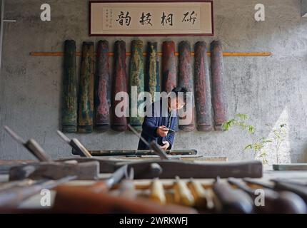 (240313) -- NANCHANG, 13 marzo 2024 (Xinhua) -- Feng Yihua ricopre un Guqin con lacca nel suo studio di Guqin nella contea di Yihuang, nella provincia di Jiangxi, nella Cina orientale, 8 marzo 2024. Il Guqin, uno strumento cinese tradizionale a sette corde a pizzico, vanta una storia di oltre 3.000 anni. Feng Yihua, un produttore di Guqin di 38 anni, proviene dalla contea di Yihuang, nella provincia di Jiangxi nella Cina orientale. Influenzato dalla sua famiglia, Feng iniziò a studiare il Guqin all'età di 18 anni. In seguito si trasferì a Shanghai per fare l'apprendista sotto un maestro nell'artigianato di Guqin. "Creare un Guqin a mano richiede una lacca grezza, che inizialmente Foto Stock