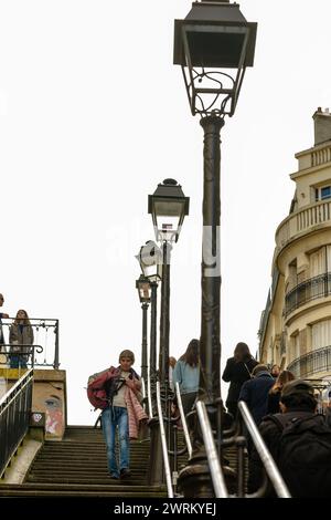 Parigi, Francia - 17 febbraio 2024: Veduta dei turisti che camminano su e giù per le pittoresche scale con lanterne parigine nel Montmartre Parigi Foto Stock