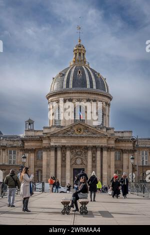 Parigi, Francia - 03 08 2024: Veduta dell'Institut de France dal Pont des Arts con un turista intorno Foto Stock