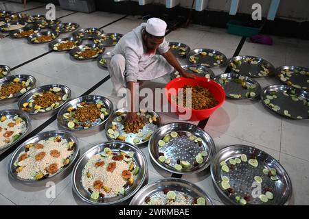 I volontari preparano il cibo Iftar per i devoti musulmani prima di rompere il loro digiuno durante il mese santo del Ramadan alla Moschea Nazionale Baitul Mukarram a Dacca, Bangladesh, il 13 marzo 2024 Foto Stock