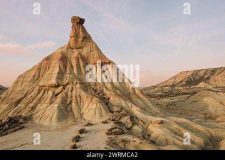 La calda luce del tramonto bagna le formazioni rocciose uniche delle Bardenas Reales, creando un paesaggio sereno e ultraterreno a Navarra, Spagna. Foto Stock