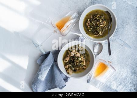 Vista dall'alto del tradizionale piatto georgiano, il chakapuli, con carne stufata con vino bianco, prugne verdi crostate e un mix di erbe fresche come il dragoncello, Foto Stock