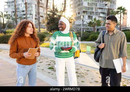 Un gruppo di studenti diversi con una donna afroamericana che indossa un hijab, un uomo ispanico e una donna caucasica si impegnano in una vivace discussione Foto Stock