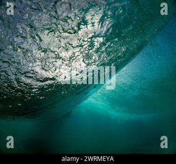 La parte inferiore di un'onda potente catturata con dettagli squisiti, evidenziando le texture e i colori della natura dinamica dell'oceano Foto Stock