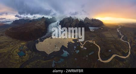 Scatto aereo panoramico mozzafiato che cattura il vasto ghiacciaio Vatnajokull davanti a un tramonto spettacolare, con tortuosi fiumi e l'aspra terra islandese Foto Stock