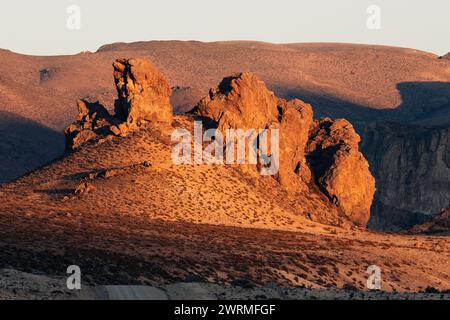 La calda luce del tramonto bagna le formazioni rocciose uniche nei paesaggi desolati della Patagonia argentina, evidenziandone l'aspra bellezza Foto Stock