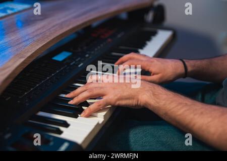 Le mani di un musicista irriconoscibile che suona una melodia su un sintetizzatore moderno durante una sessione di registrazione in studio, con un assaggio di interfac digitale Foto Stock