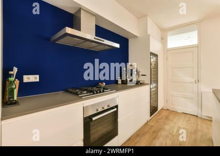 una cucina con una parete con accenti blu e armadi bianchi Foto Stock