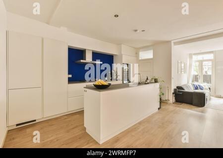 una cucina con armadi bianchi e una parete d'accento blu Foto Stock