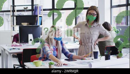 Immagine di punti interrogativi su diverse donne d'affari che indossano maschere facciali e utilizzano il computer Foto Stock