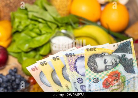 Costo della vita in Romania, prezzi alimentari, concetto di economia e budget, denaro rumeno tenuto in mano davanti ai prodotti alimentari, aumento dell'inflazione nei rom Foto Stock