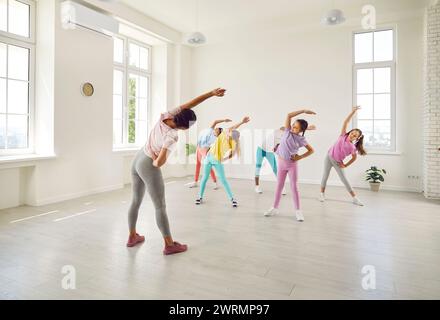 Coreografa donna che mostra alle sue studentesse esercizi di stretching in studio di danza. Foto Stock