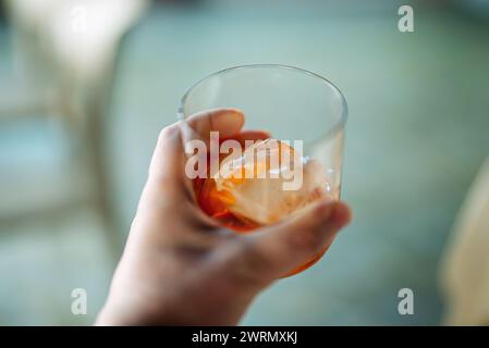 Un uomo regala un classico cocktail Negroni con ghiaccio. Foto Stock