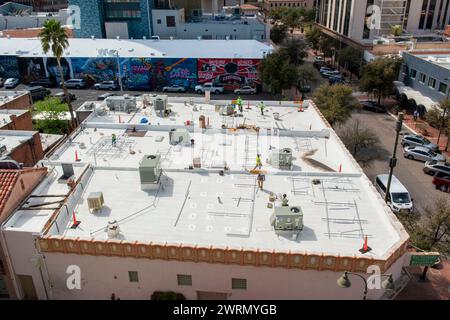 A metà dei grattacieli, gli operai dipingono tetti piani con vernice elastomerica riflettente per respingere le piogge e il caldo estivo di Tucson, Arizona Foto Stock