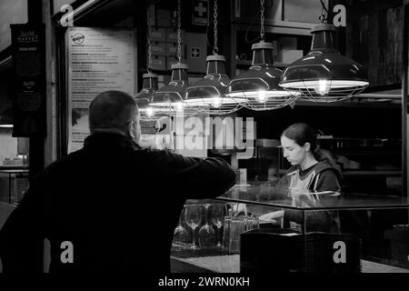 La barmaid serve aperitivi al Mercado da Ribeira di Lisbona, Portogallo Foto Stock