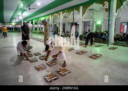 I volontari distribuiscono e organizzano file di pasto "iftar" per i devoti per rompere il digiuno, durante il mese sacro del Ramadan, a Burha Jame Masjid, il 13 marzo 2024 a Guwahati, Assam, India. Crediti: David Talukdar/Alamy Live News Foto Stock