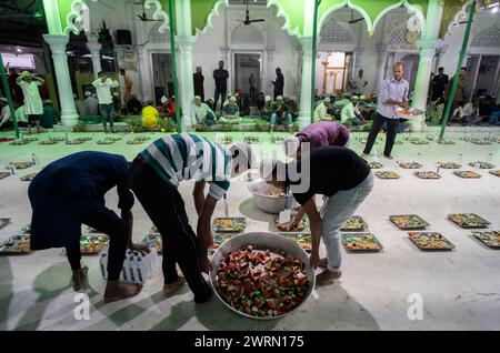 I volontari distribuiscono e organizzano file di pasto "iftar" per i devoti per rompere il digiuno, durante il mese sacro del Ramadan, a Burha Jame Masjid, il 13 marzo 2024 a Guwahati, Assam, India. Crediti: David Talukdar/Alamy Live News Foto Stock