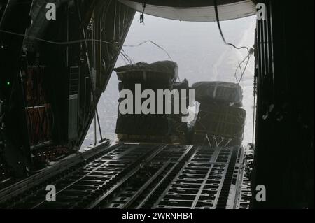 Gaza, Israele. 11 marzo 2024. Pallet di aiuti umanitari cadono dalla stiva di carico di un aereo C-130J Super Hercules dell'aeronautica statunitense lungo la costa, 11 marzo 2024 sopra la Striscia di Gaza, territori palestinesi. Gli aiuti alimentari saranno lanciati in aria ai rifugiati palestinesi intrappolati dalla guerra israeliana contro Hamas. Credito: SSgt. Jasmonet Holmes/US Airforce Photo/Alamy Live News Foto Stock