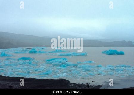 Iceberg dal ghiacciaio Fjallsjokull in fusione sotto la pioggia, Islanda Foto Stock