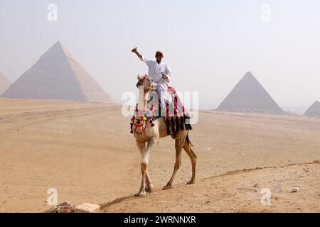 Cairo Giza, Egitto - 24 ottobre 2024 - giro in cammello nel deserto del Sahara. Foto di un beduino e del suo cammello vicino alle piramidi di Giza su un beauti Foto Stock