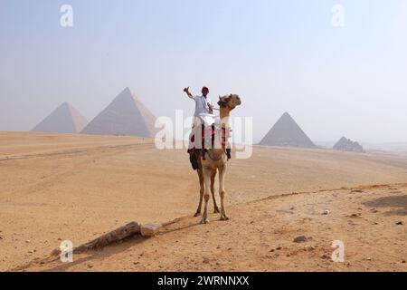 Cairo Giza, Egitto - 24 ottobre 2024 - giro in cammello nel deserto del Sahara. Foto di un beduino e del suo cammello vicino alle piramidi di Giza su un beauti Foto Stock