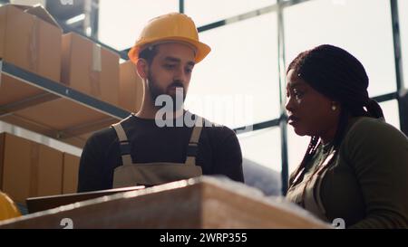 Responsabile del team di magazzino che svolge la formazione introduttiva al nuovo tirocinante, insegnandogli le misure di sicurezza sulle corsie dell'area di stoccaggio. Manager esegue un tutorial di orientamento per tirocinante Foto Stock