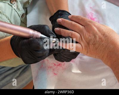 Rimozione manicure dei residui di vernice vecchia con piccolo trapano di precisione per unghie permanenti Foto Stock