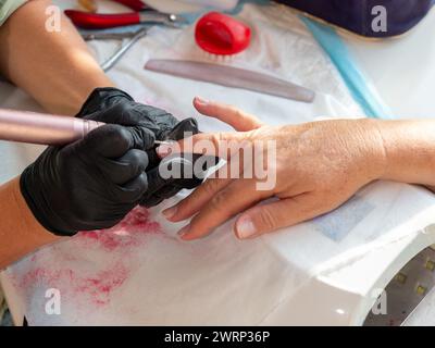 Rimozione della vernice vecchia con un trapano per la vernice permanente per unghie Foto Stock