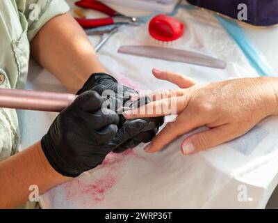 Rimozione della vernice vecchia con un trapano per la vernice permanente per unghie Foto Stock