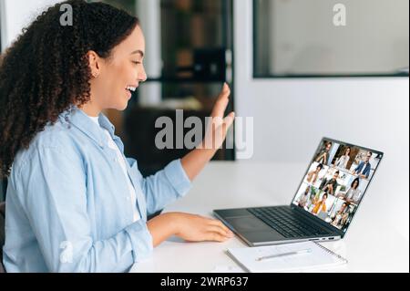 Videochiamata, brainstorming di gruppo. Imprenditrice brasiliana o ispanica, team leader, seduta sul posto di lavoro di fronte a un laptop, in videoconferenza online con team multirazziale Foto Stock