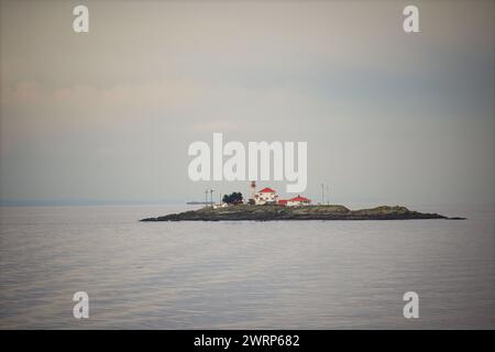 Vista distante del faro di Entrance Island su Entrance Island, un isolotto roccioso lungo l'Inside Passage nello stretto di Georgia vicino all'isola di Vancouver Foto Stock