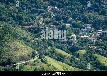 Vista aerea della vegetazione verde della foresta atlantica con il quartiere Parque da Serra e l'autostrada Washington Luiz tra le giornate di sole estive. Foto Stock